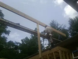 Carpenter setting a ridge beam over a new addition frame — Ice Dam Removal by Roofing Brothers in Bracey