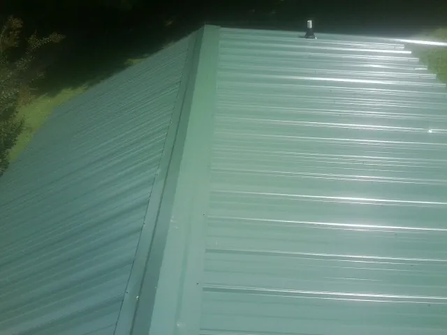 New green metal panels meeting at the ridge of a roof — Flat Roof Repair work by our crew in Bracey