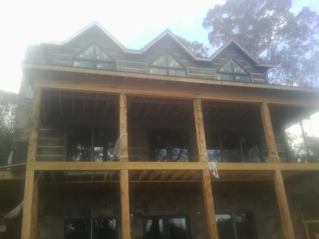 Dormers and porch framing on a large log home under construction — Roof Coating work by our crew in Bracey