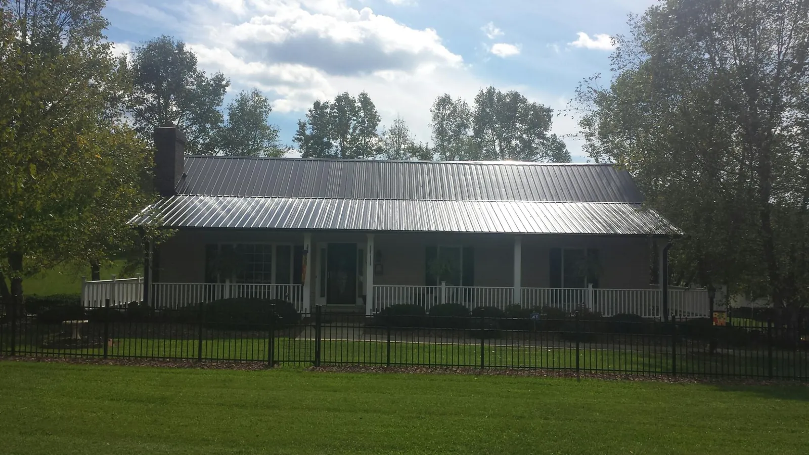 Gray metal roof on a brick ranch with a full width front porch — Gutter Guard Installation work by our crew in Bracey