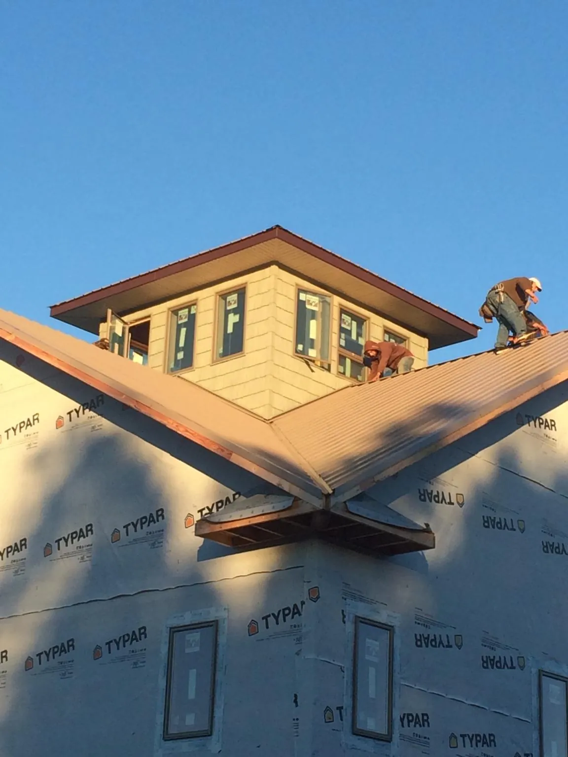 Roofers working around a rooftop cupola on a new metal roof at sunset — Roof Waterproofing in Bracey by Roofing Brothers